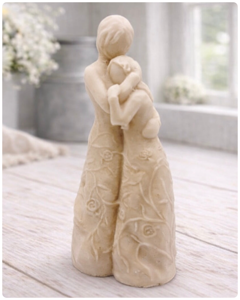 handmade vegan soap, sculpted as a mother and daughter in a tender standing embrace, featuring an intricate embossed floral and vine pattern on their dresses.