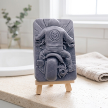 Load image into Gallery viewer, A rectangular handmade vegan soap featuring a detailed high-relief carving of a biker from behind riding a motorcycle, wearing a leather-style jacket with a skull emblem on the back, displayed on a wooden easel.
