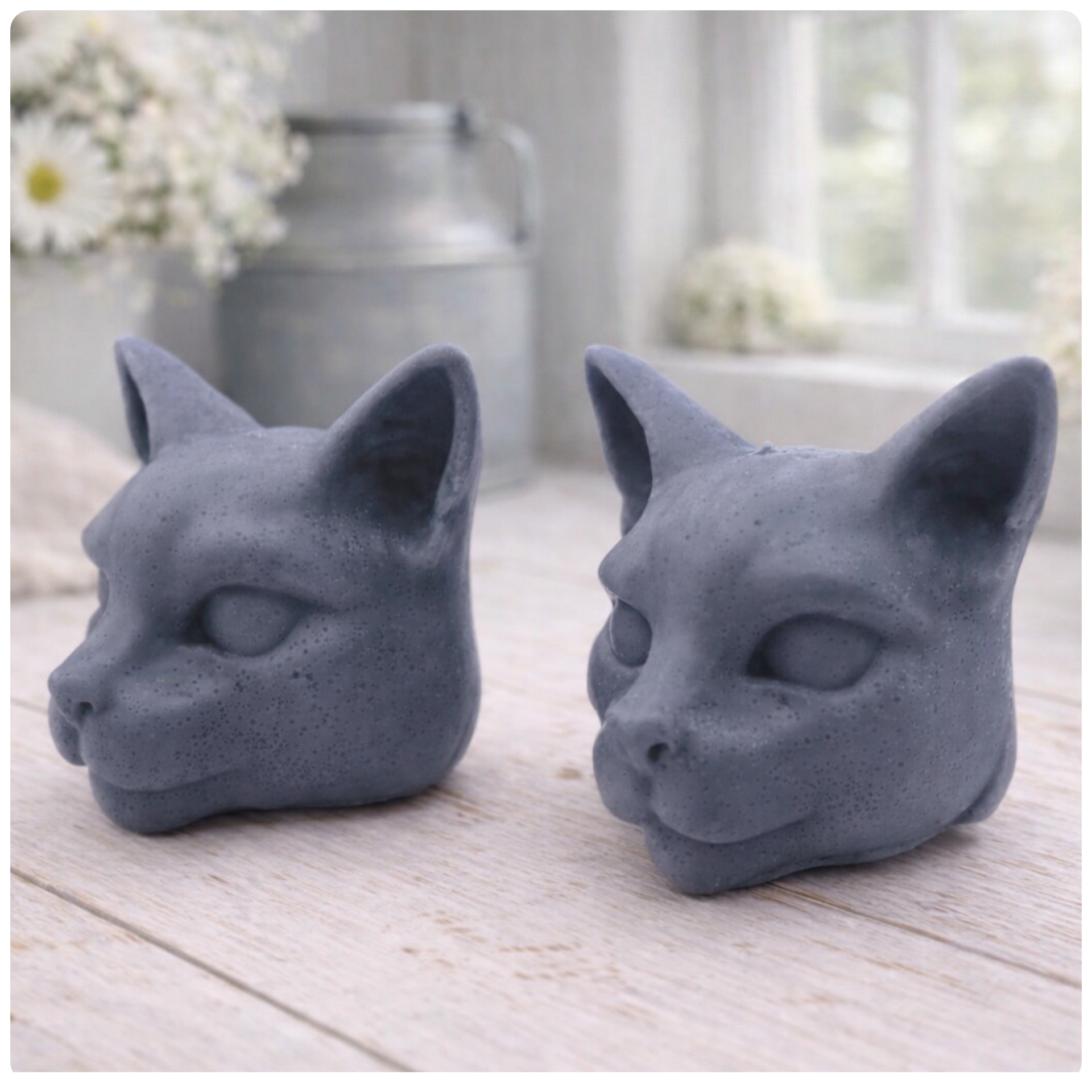 two handmade vegan soaps in the shape of Siamese cat heads, featuring elegant pointed ears and sleek facial features, displayed on a neutral cloth in a bright farmhouse decor setting.