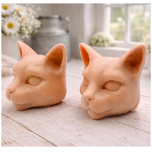 Load image into Gallery viewer, two handmade vegan soaps in the shape of Siamese cat heads, featuring elegant pointed ears and sleek facial features, displayed on a neutral cloth in a bright farmhouse decor setting.
