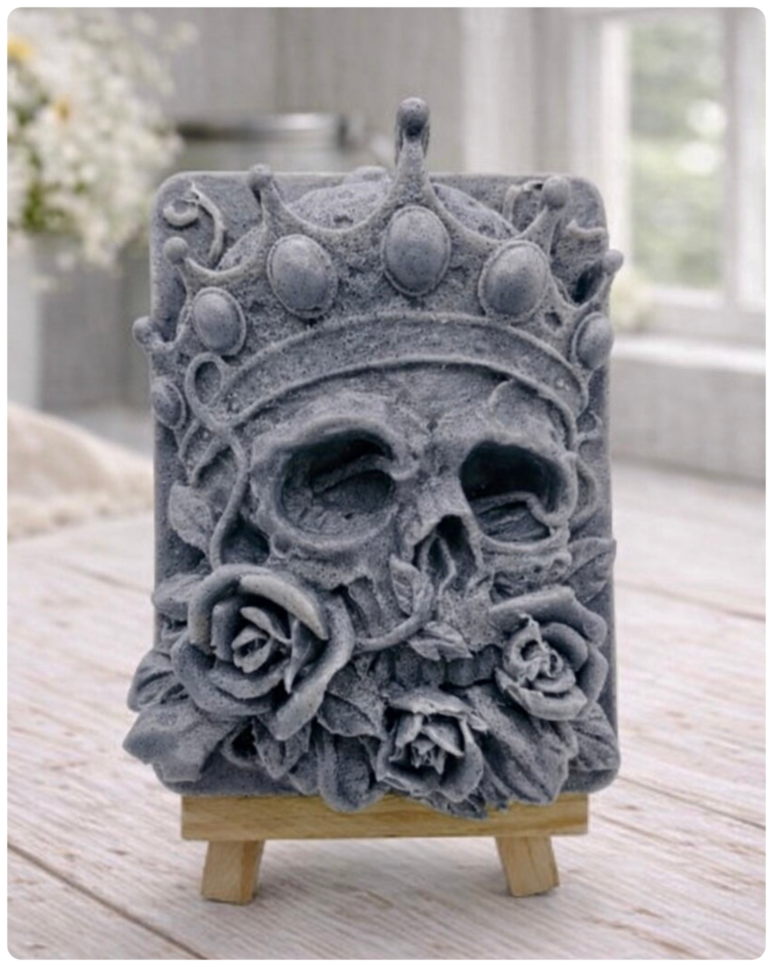 handmade vegan soap gift featuring a detailed relief of a skull wearing a crown, surrounded by a border of roses, displayed on a small wooden easel.