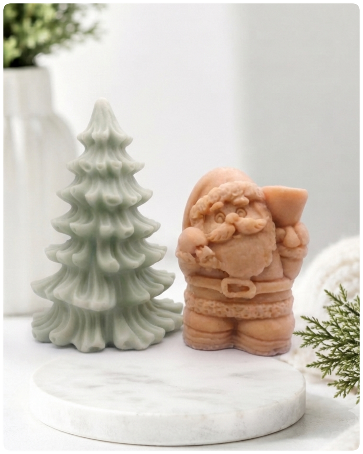 A duo of handmade vegan soaps featuring a Father Christmas figure with standing next to a mint-green tiered 3D Christmas tree, displayed in a bright farmhouse setting.