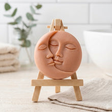 Load image into Gallery viewer, handmade vegan soap featuring a circular relief sculpture of a crescent moon and sun with peaceful intertwined faces
