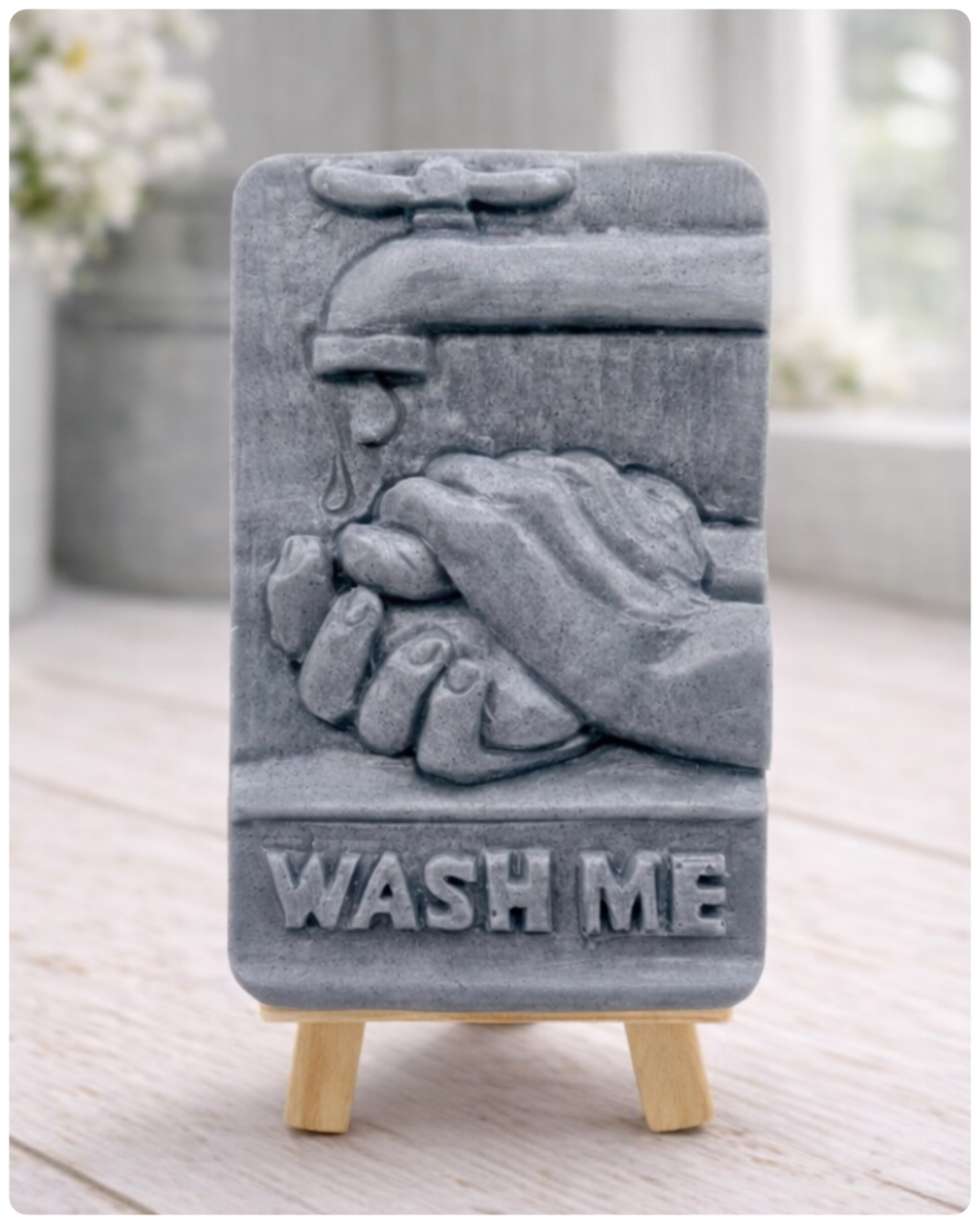Gray soap bar with hands and 'Wash Me' text on a stand