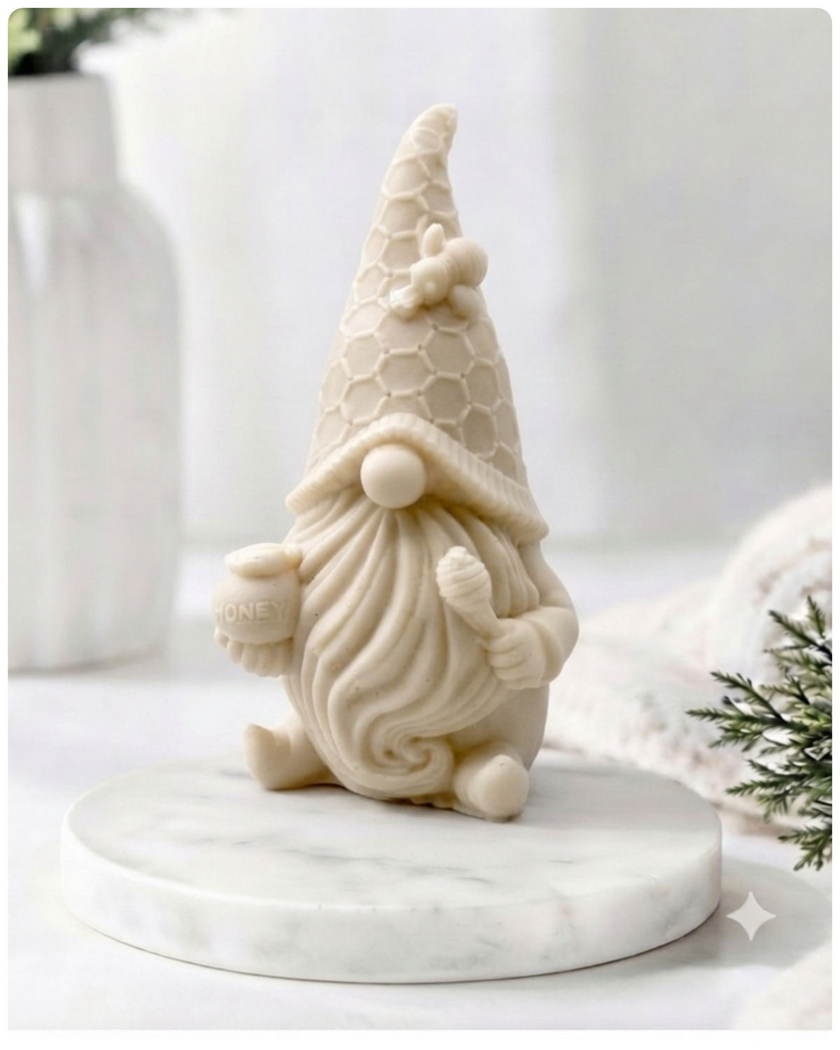 A handmade vegan soap in the shape of a gnome with a long beard, wearing a honeycomb-patterned hat with a bee, holding a honey pot and dipper.