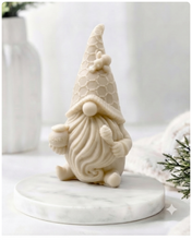 Load image into Gallery viewer, A handmade vegan soap in the shape of a gnome with a long beard, wearing a honeycomb-patterned hat with a bee, holding a honey pot and dipper.
