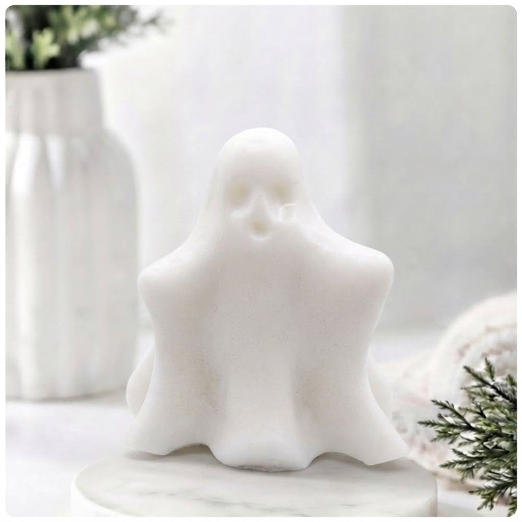 A white ghost-shaped decorative soap figurine with a smooth matte finish, displayed on a round marble-like base against a soft, blurred white background with subtle home decor elements.