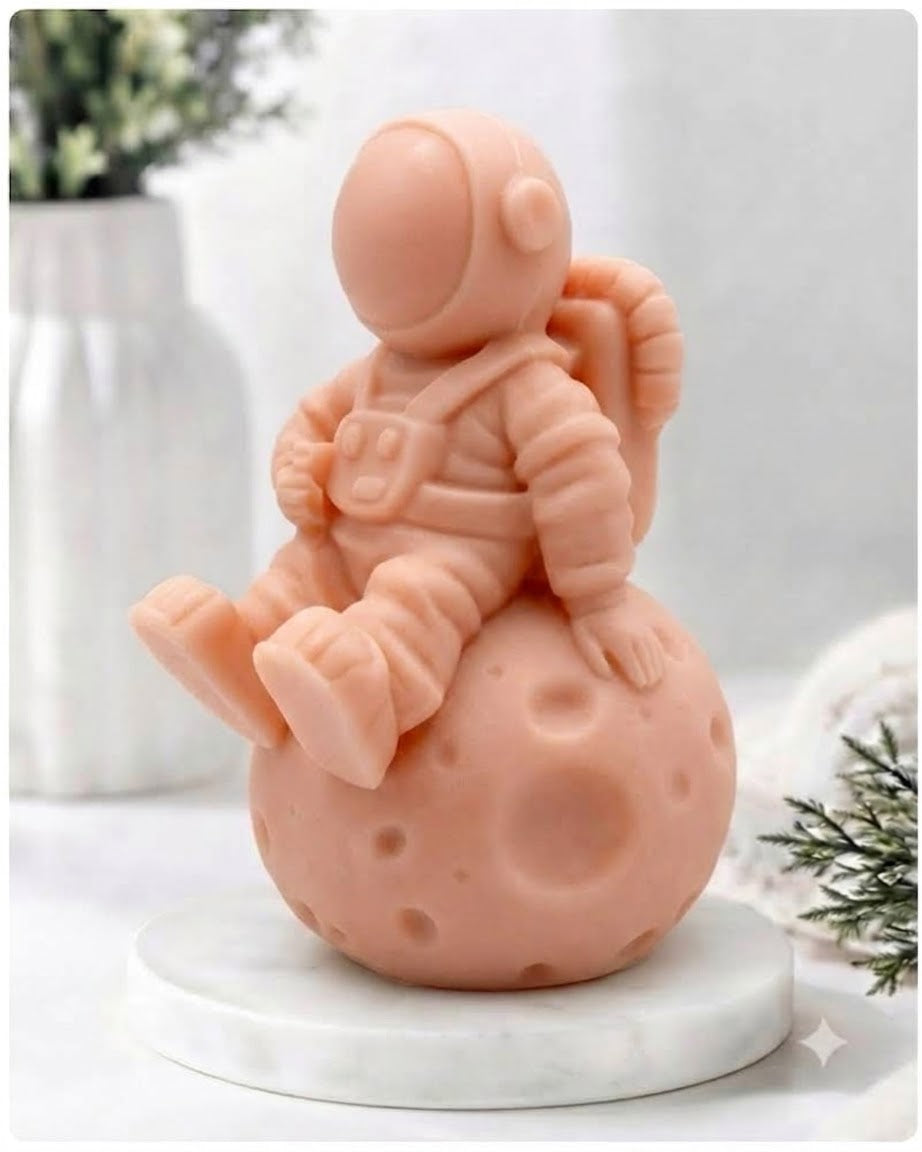 handmade vegan soap in the shape of a realistic astronaut sculpture sitting on the moon, featuring detailed spacesuit textures and craters on the lunar surface, displayed in a bright farmhouse decor setting.