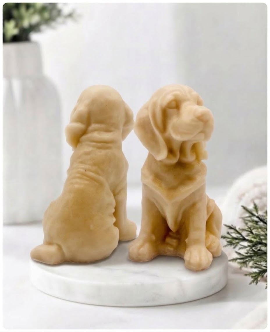 Two yellow Golden Retriever soap sitting on a white marble display stand with a soft bathroom background.