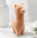 handmade vegan soap in the shape of a realistic standing alpaca sculpture, featuring detailed curly wool texture and a smiling face, displayed on a rustic white wooden surface in a bright farmhouse decor setting.