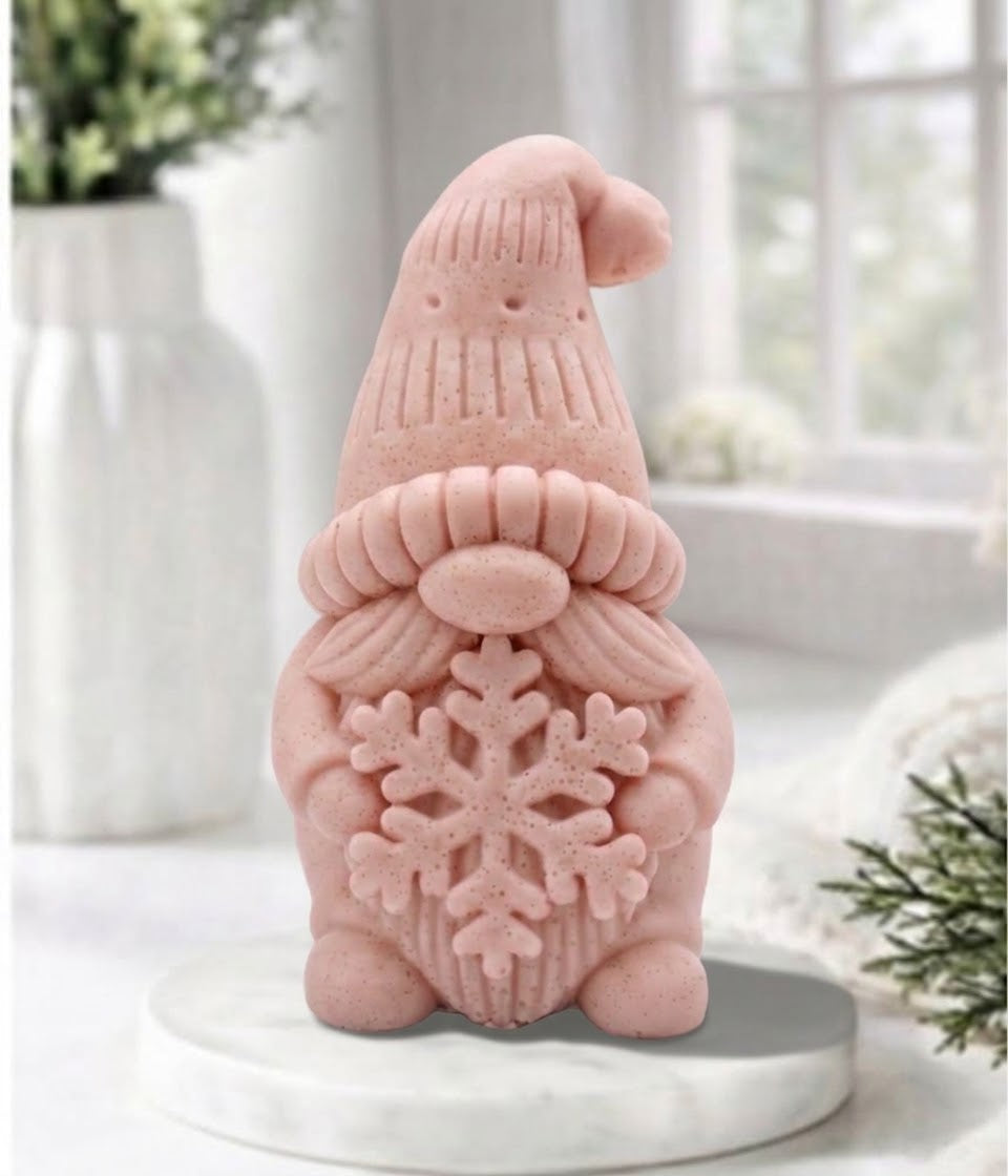 handmade pink vegan soap in the shape of a winter gnome sculpture holding a large snowflake, featuring a tall textured hat and a bushy moustache 