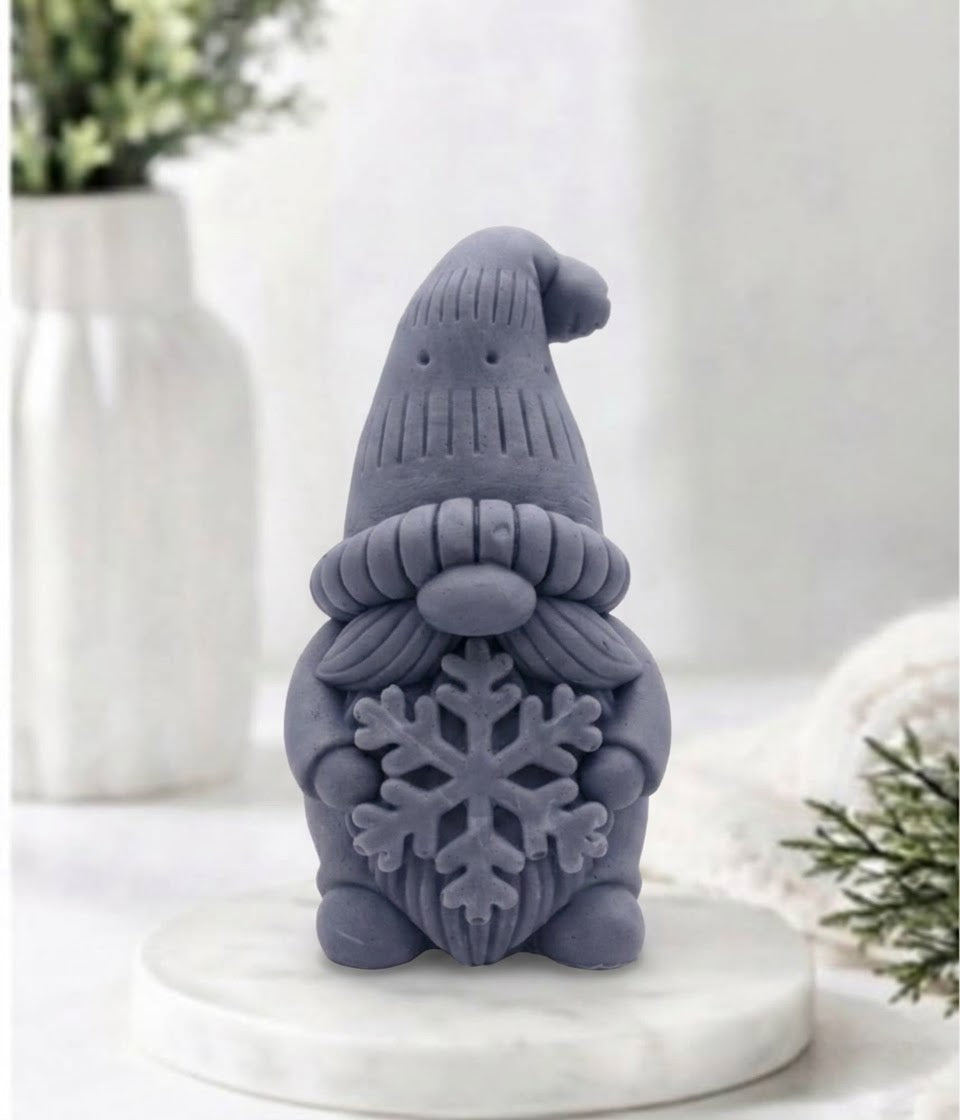 handmade charcoal vegan soap in the shape of a winter gnome sculpture holding a large snowflake, featuring a tall textured hat and a bushy moustache 