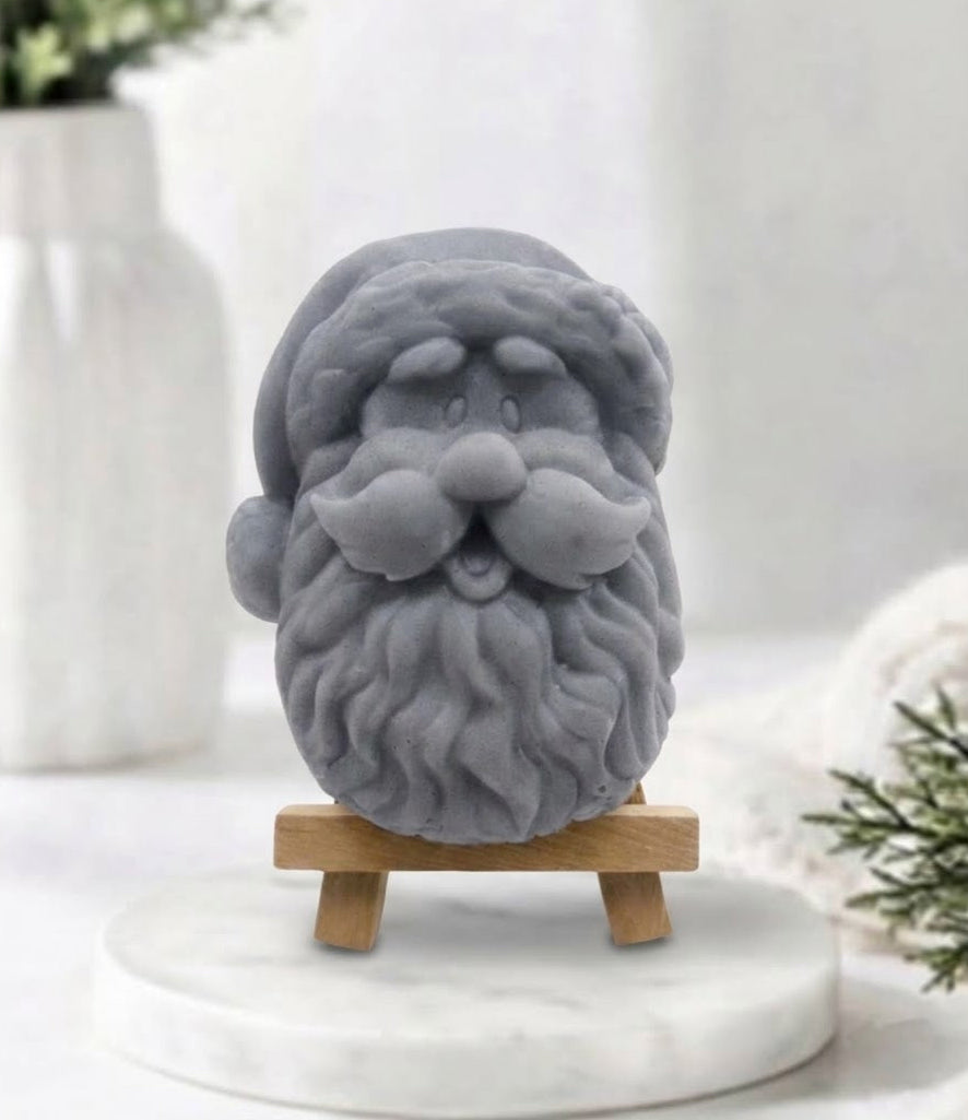 handmade charcoal vegan soap sculpted in the shape of Father Christmas's head, featuring a detailed curly beard, a jolly moustache, and a classic Santa hat.
