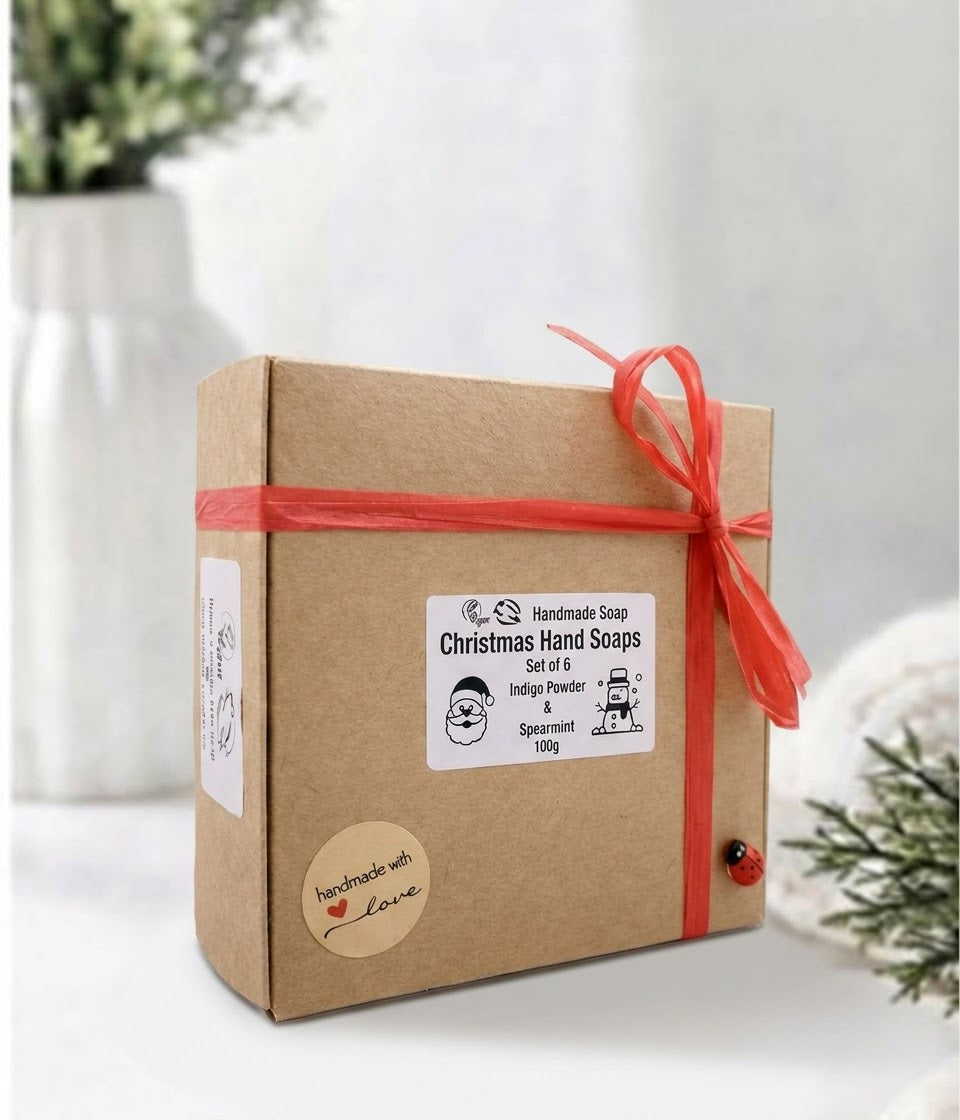 Box of Christmas hand soaps with a red ribbon and a cute wooden ladybird on a wooden surface