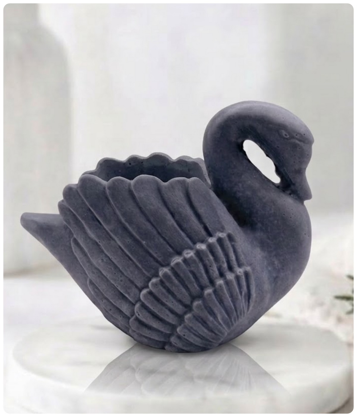 A side profile of a charcoal swan soap bar resting on a marble pedestal.