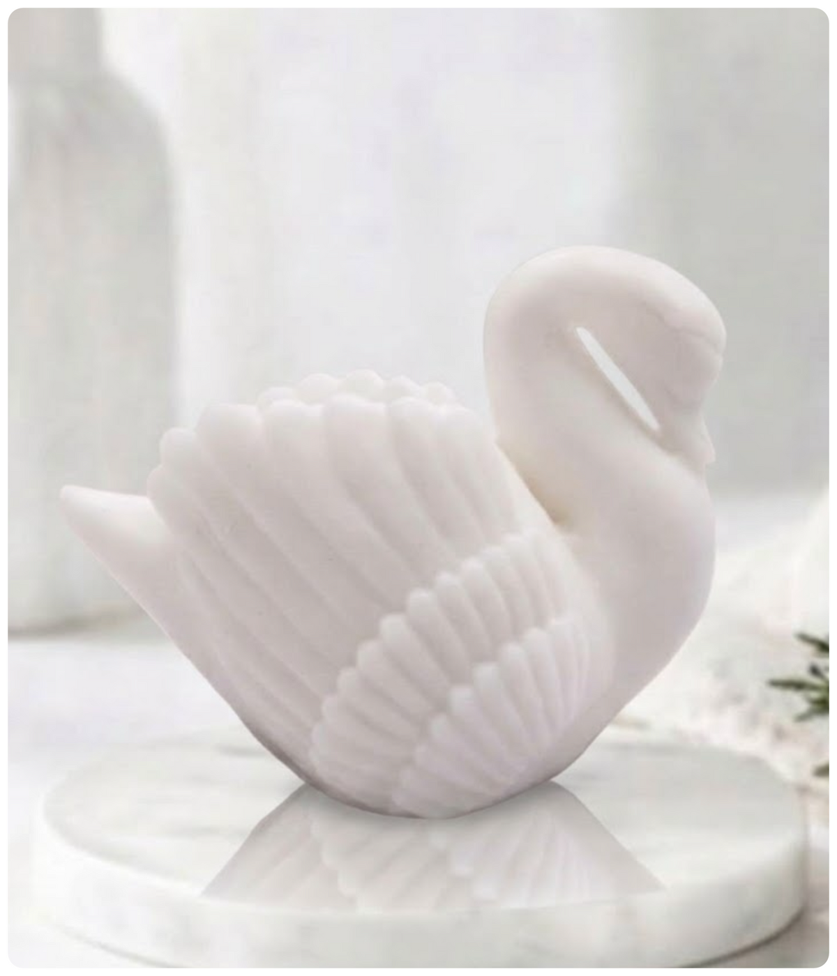 A pure white swan soap bar resting on a polished marble display tray.