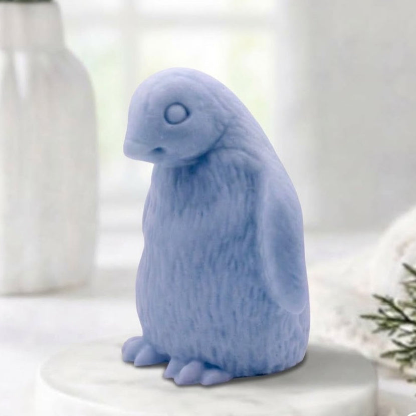 Handmade light blue indigo penguin-shaped soap bar displayed on a white marble tray.