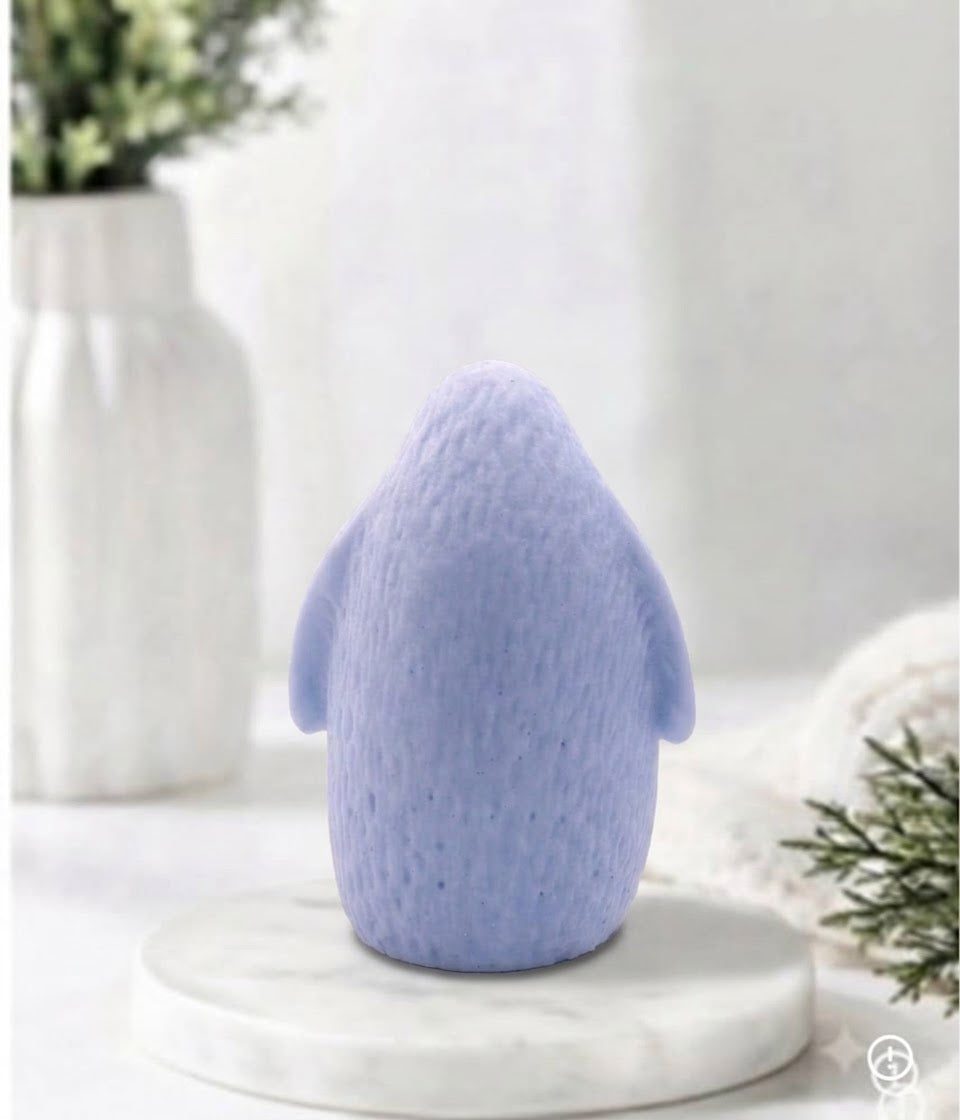 Rear view of a handmade light blue indigo penguin-shaped soap showing textured feather details.