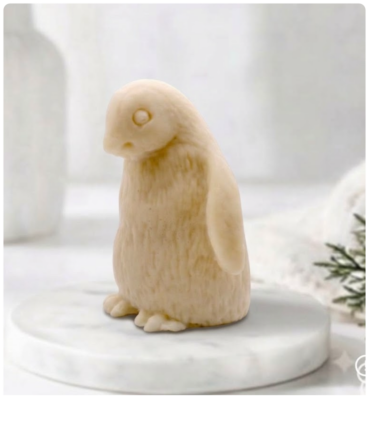 yellow clay penguin-shaped soap bar shown from a side profile on a marble tray.