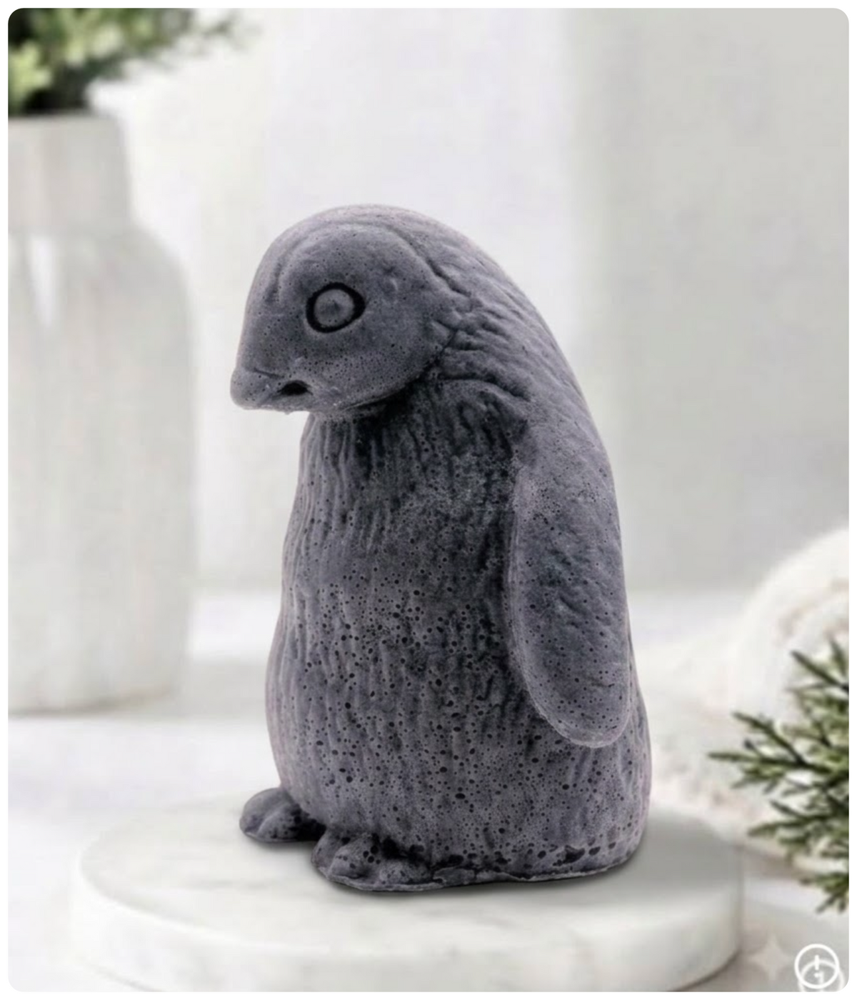 Handmade charcoal grey penguin-shaped novelty soap bar displayed on a marble tray.