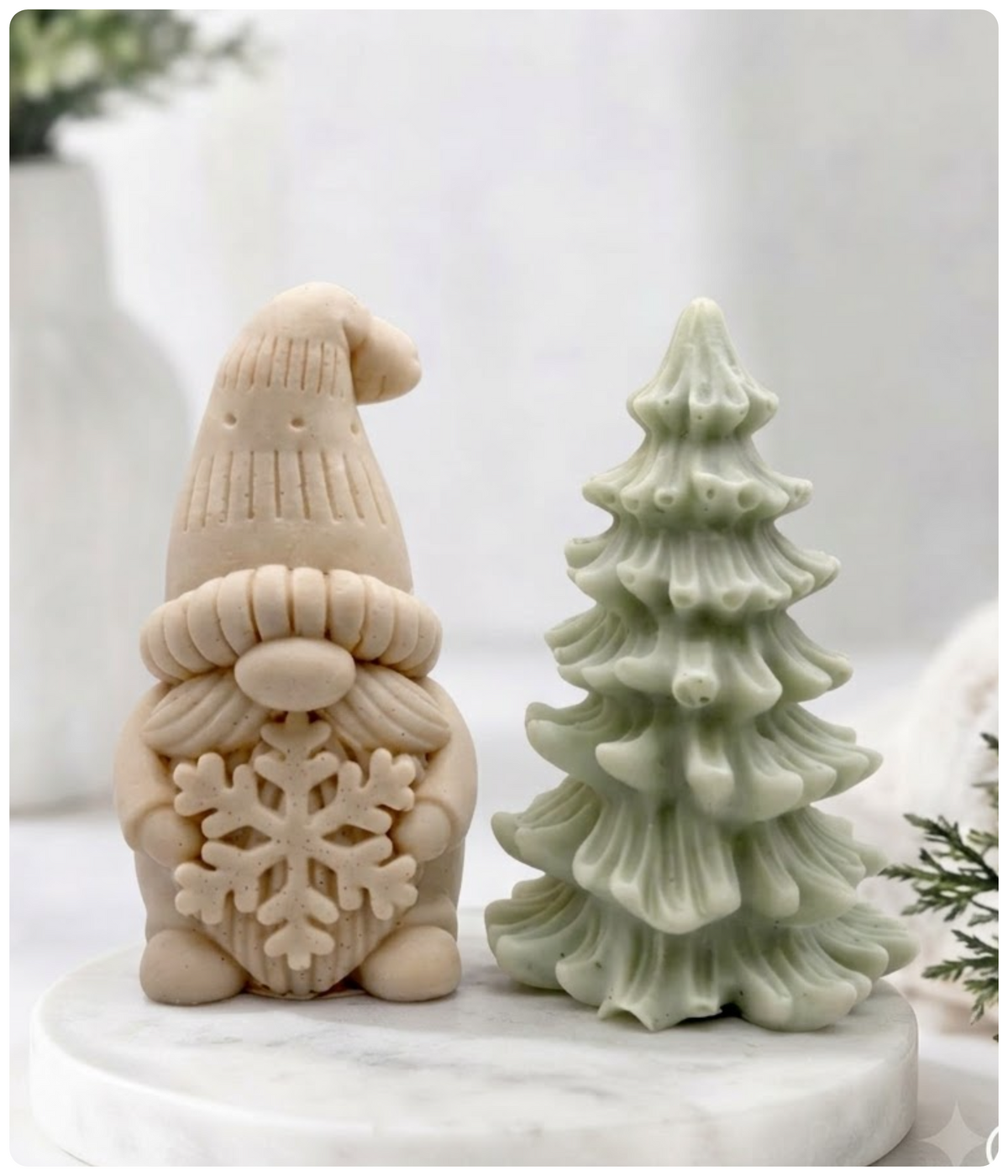 Yellow French clay gnome soap holding a large snowflake standing alongside a pale green Christmas tree soap bar.
