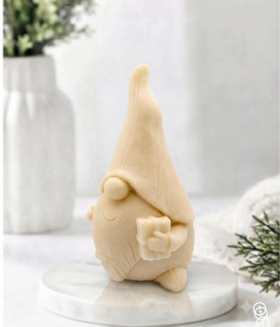 Side profile view of a yellow-coloured gnome soap bar holding a small gift box on a marble plate