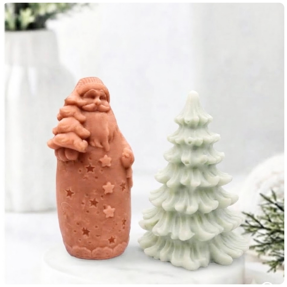 Terracotta red Santa-shaped soap bar standing alongside a green pine tree soap bar on a marble surface.