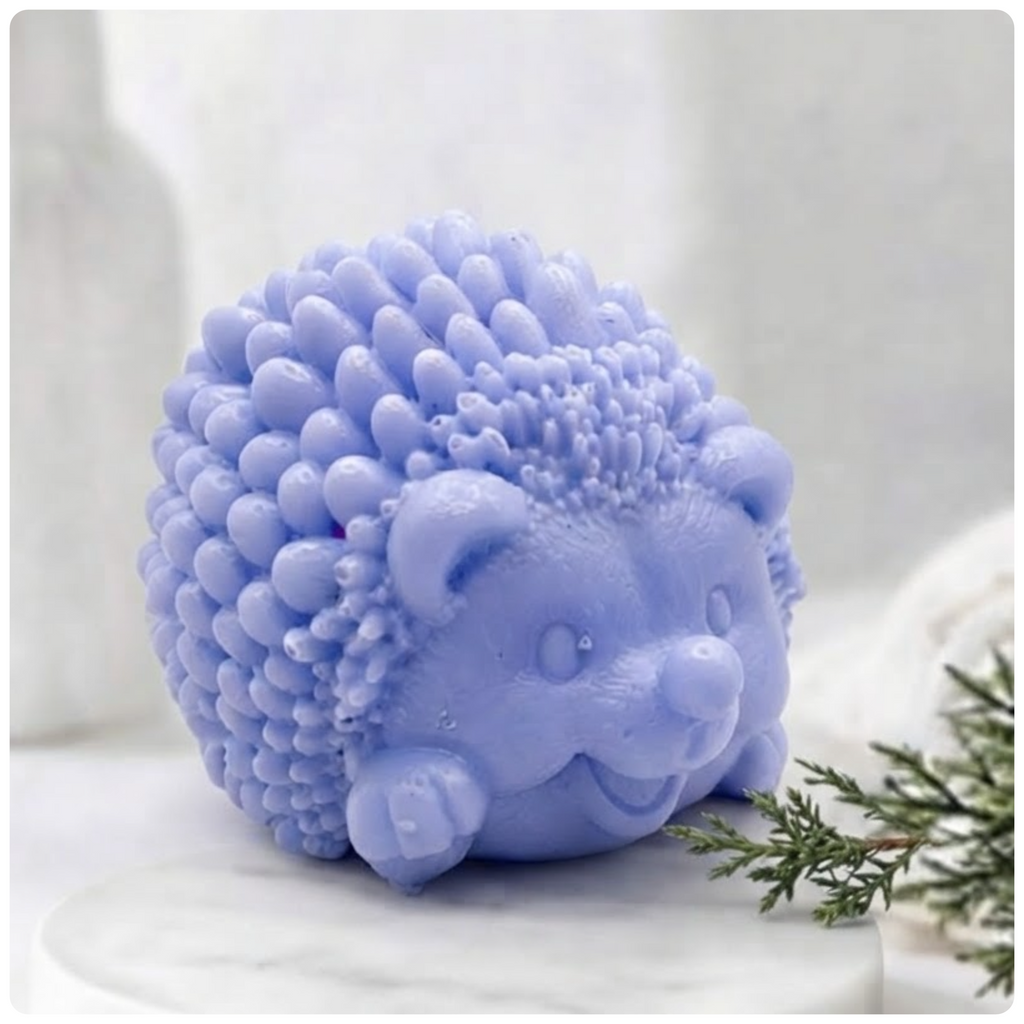 A blue, sculpted hedgehog soap figure, detailed with small spikes and a smiling face, sits on a white marble surface against a blurred bathroom background.