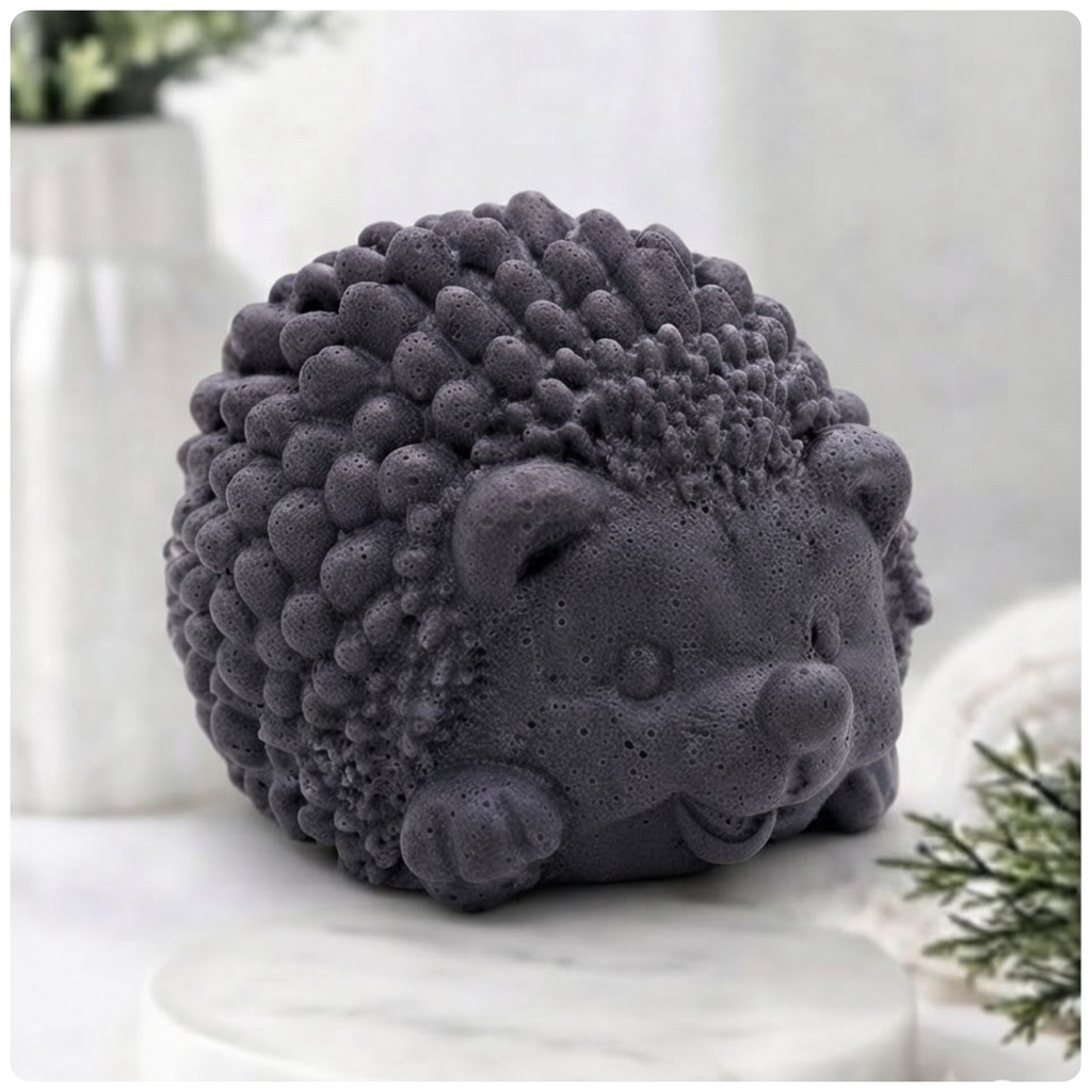 A dark grey, textured hedgehog soap figure, detailed with small spikes and a smiling face, sits on a white marble surface against a blurred bathroom background.