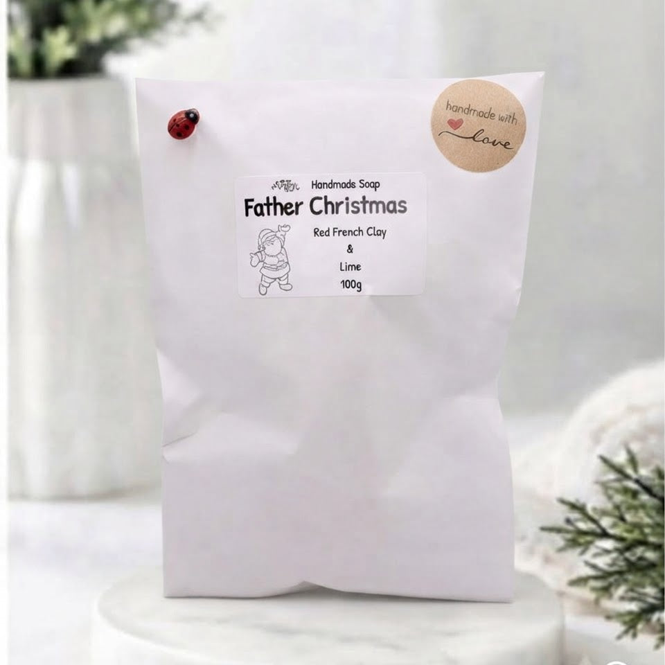 A white paper bag of 'Father Christmas' handmade soap on a white marble coaster.