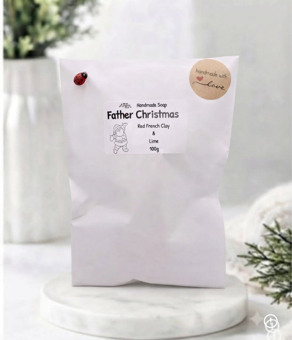 A white paper bag of 'Father Christmas' handmade soap on a white marble coaster.