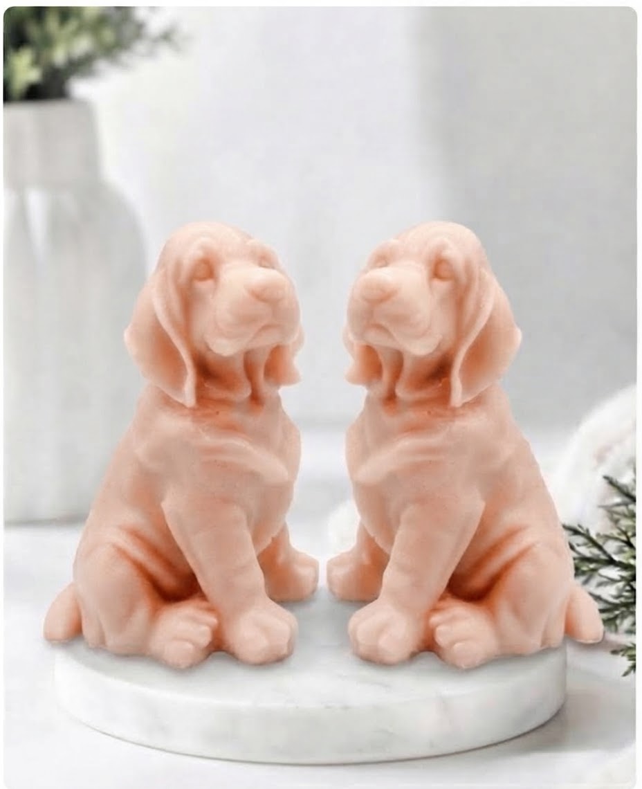 Two pink French clay bloodhound soap sitting on a white marble display stand with a soft bathroom background.