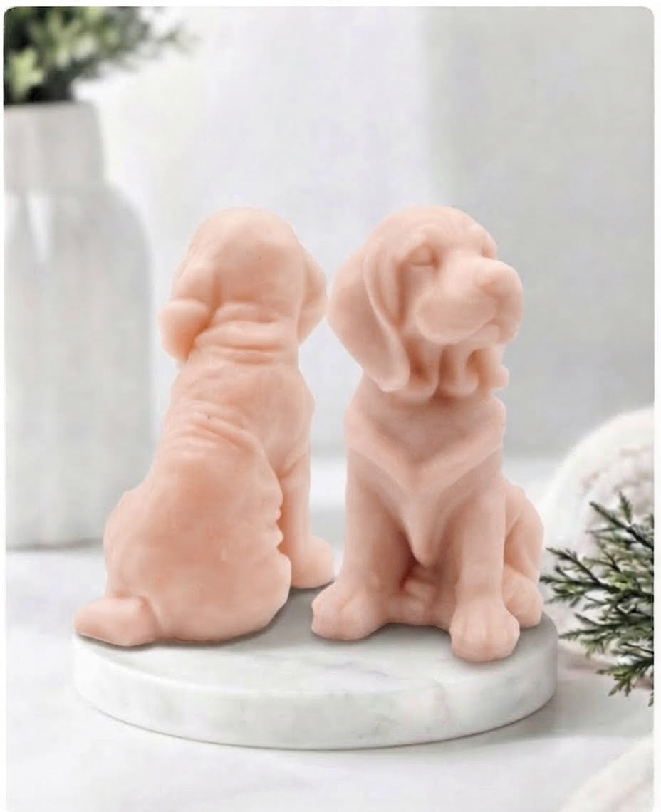 Two soft pink bloodhound soap sitting on a white marble display stand with a soft bathroom background.