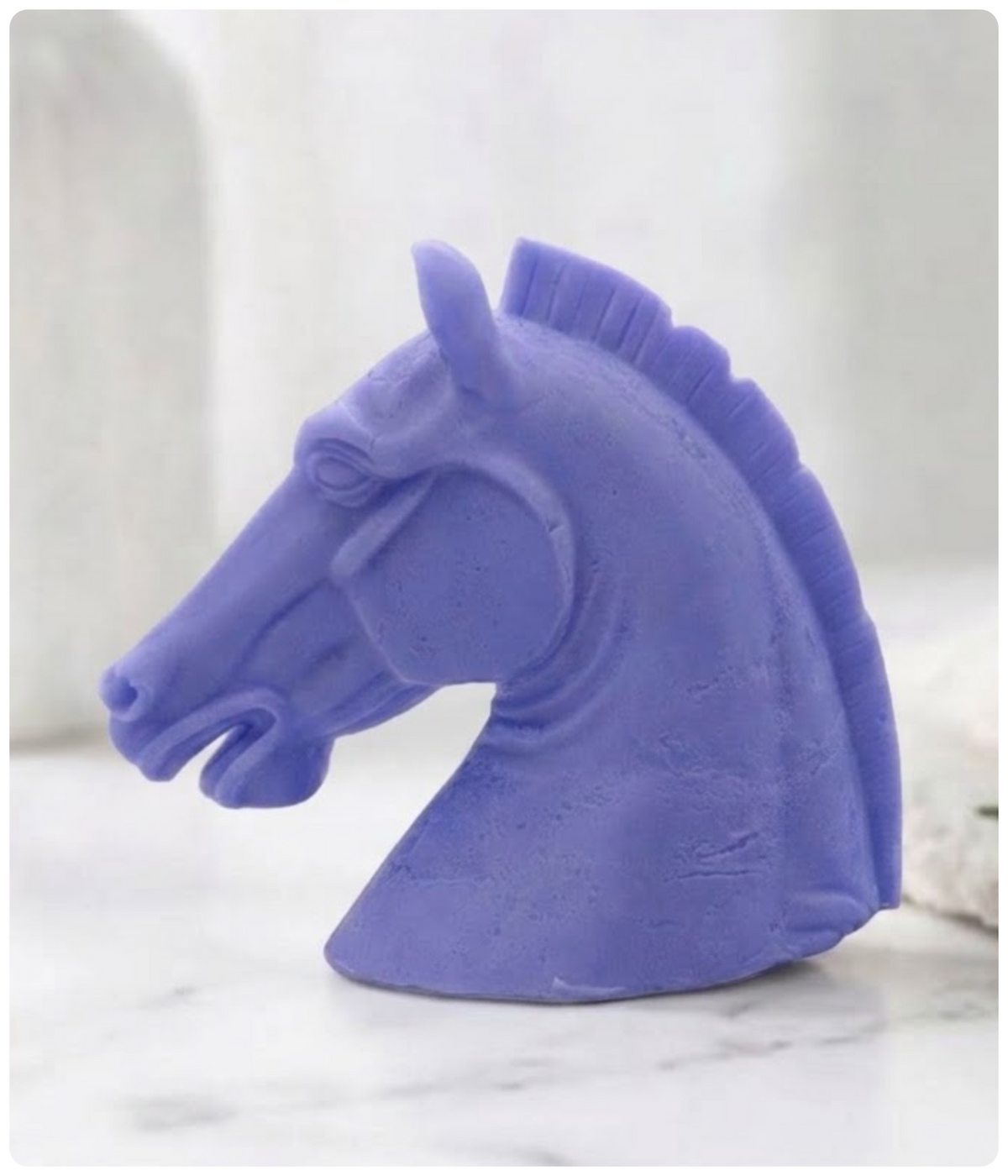 A indigo blue horse head vegan soap sculpture object shown in profile on a light marble-like surface with a soft blurred background.