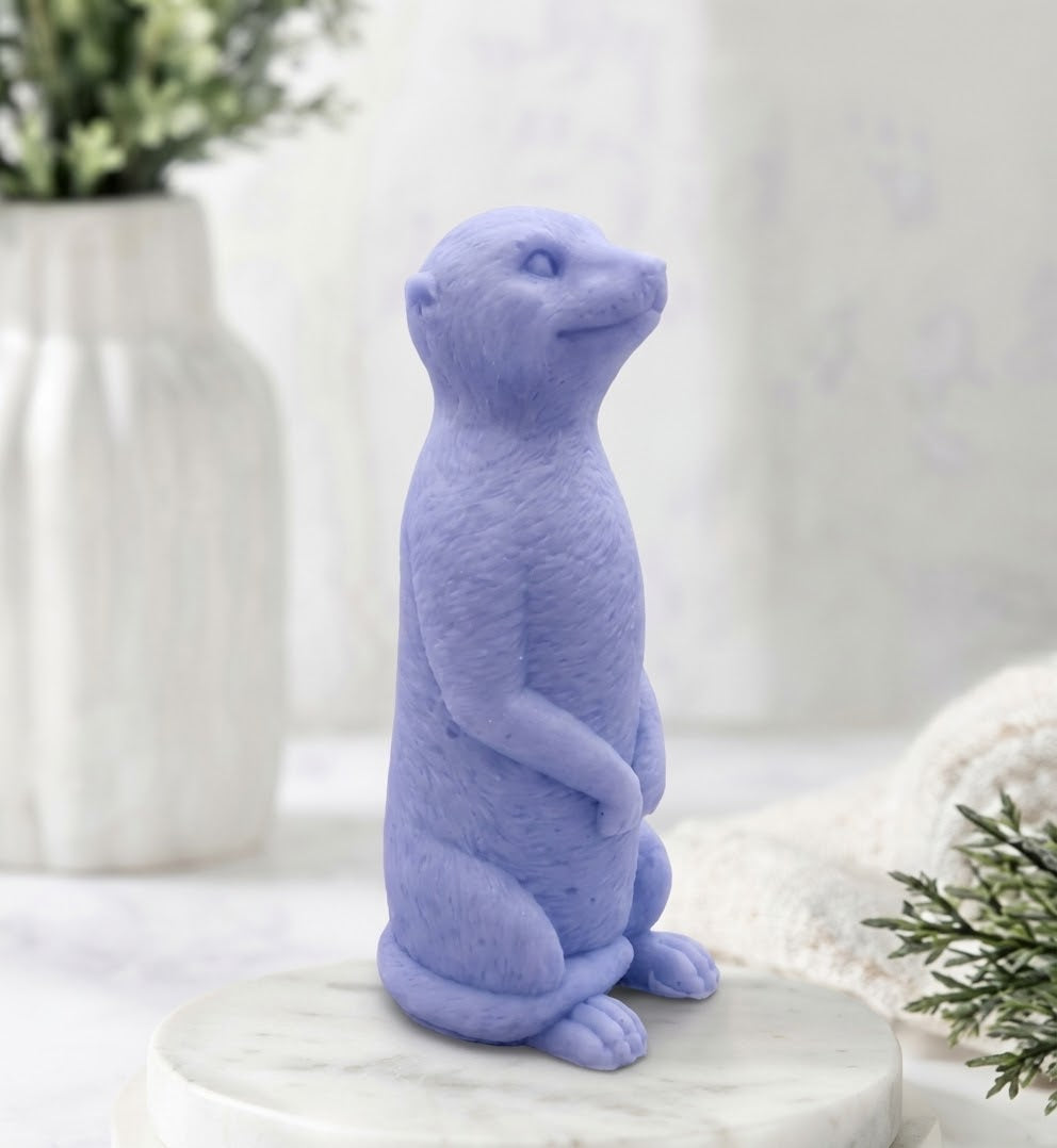 Handmade vegan meerkat soap made with natural indigo powder and displayed on a white marble plinth with bathroom decor background.