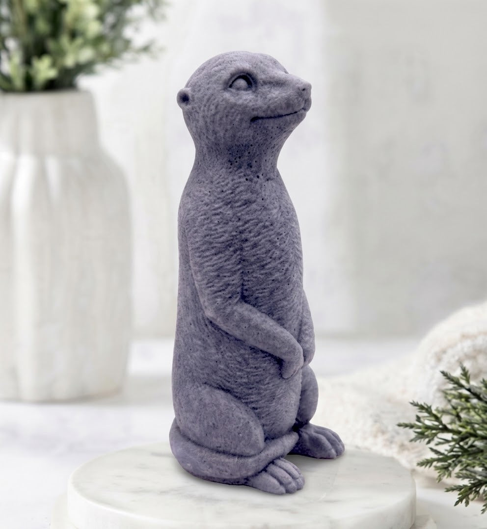 Handmade vegan meerkat soap made with activated charcoal, in a side profile standing posture resting on a white marble plinth.