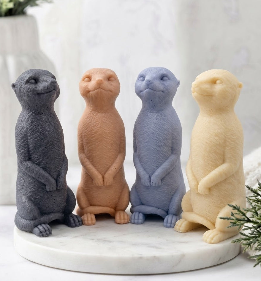 A set of four handmade vegan meerkat soaps lined up together on a marble tray.