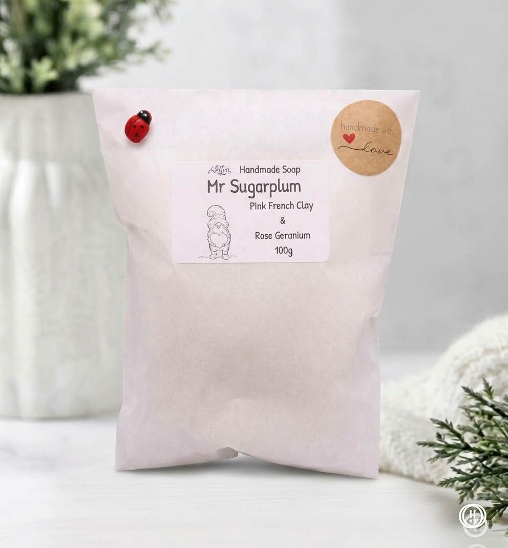 Single paper packet for handmade soap labeled "Lillian Handmade Soap - Mr Sugarplum - Pink French Clay & Rose Geranium, 100g", sealed with a "handmade with love" sticker and small ladybug.