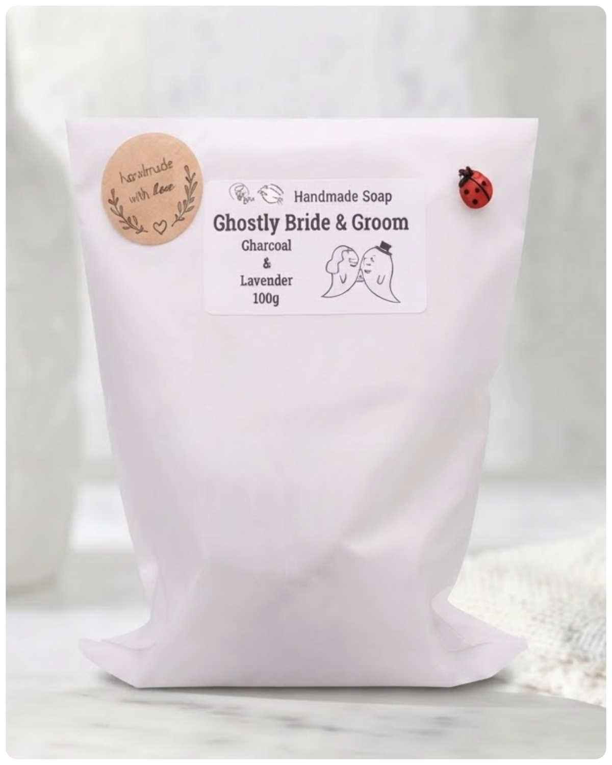 Handmade soap package labeled 'Ghostly Bride & Groom' on a wooden surface.