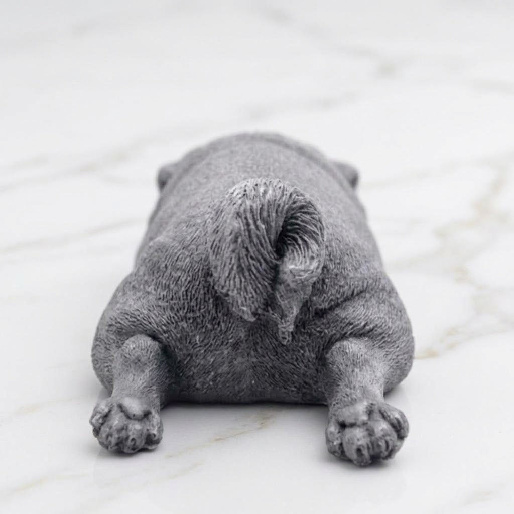 A grey pug-shaped vegan soap gift. resting on a light marble surface with a soft background.