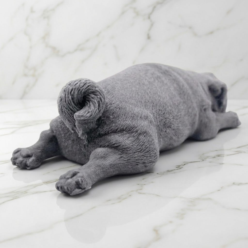 A rear view of a charcoal grey pug-shaped vegan soap gift. resting on a light marble surface with a soft background.