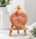 A terracotta, round vegan soap bar with a sun and moon kissing face design.