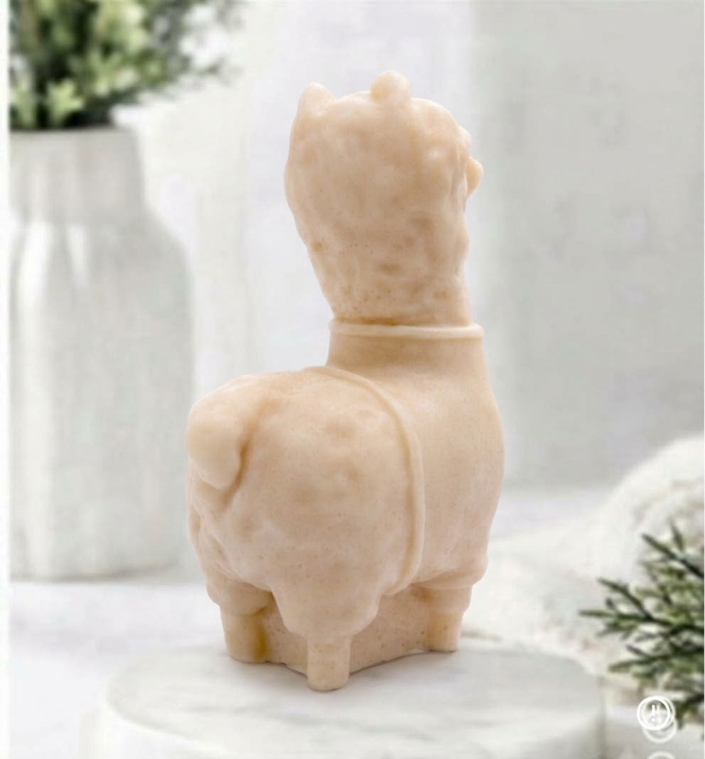 A rear view of a soft yellow coloured decorative llama / alpaca shaped vegan soap on a white surface.