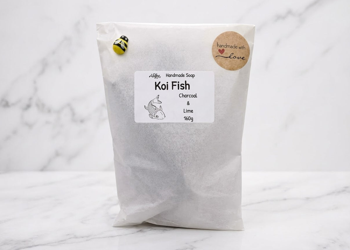 A white paper pouch of Koi Fish Charcoal & Lime activated carbon filter media, featuring a white label, a small bee sticker, and a round kraft paper seal, set against a white marble background.