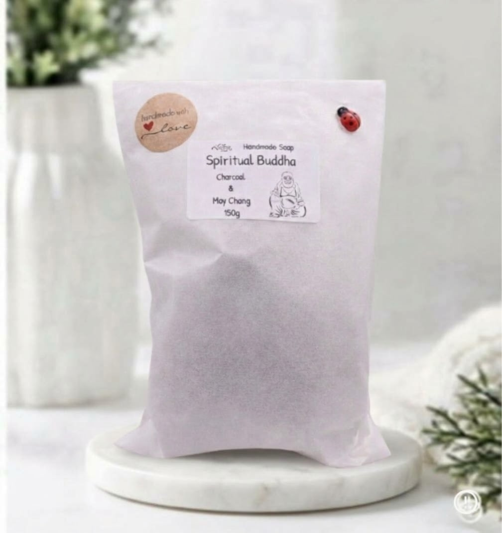 A white standing paper pouch labeled "Spiritual Buddha" charcoal and May Chang soap sitting on a white marble tray