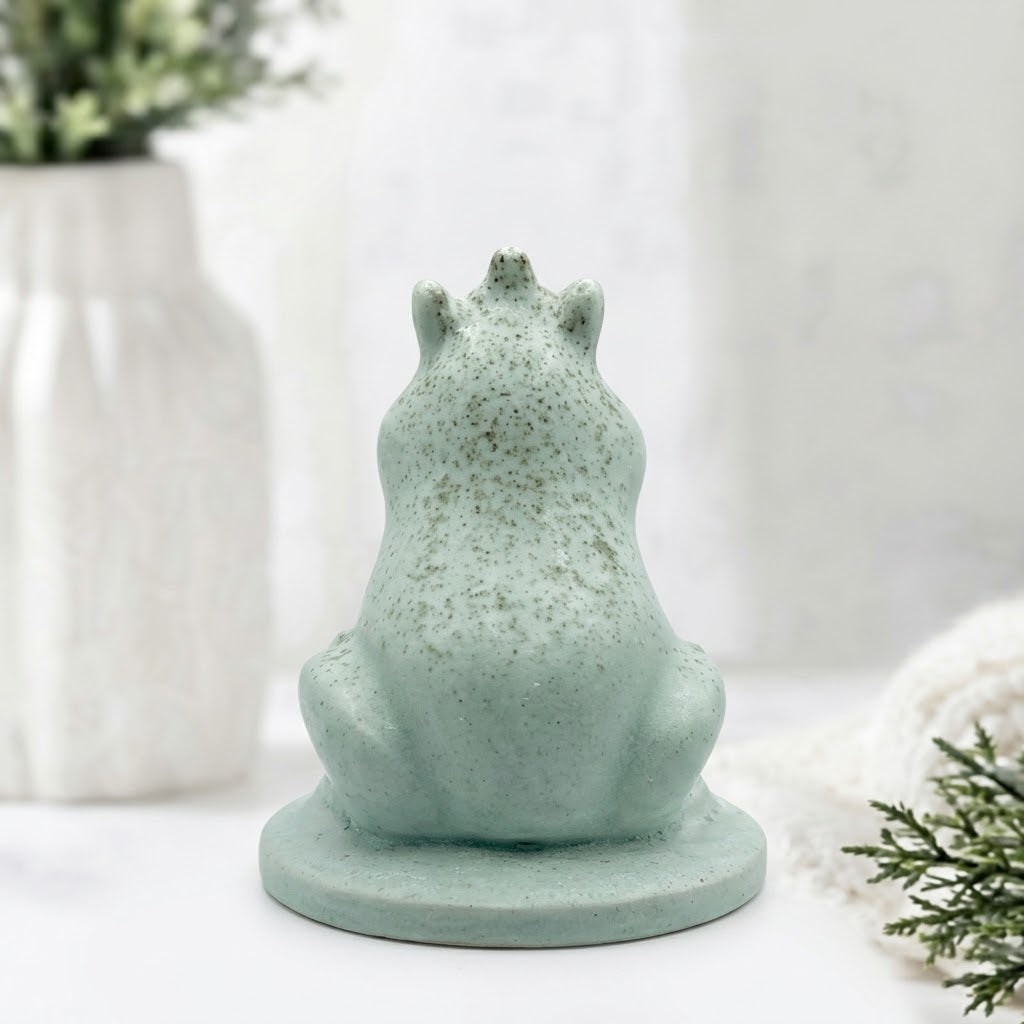 A rear view of a handmade vegan soap featuring a frog prince with a crown on his head, displayed on a white background