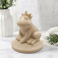 A side view of a soft yellow handmade vegan soap featuring a frog prince with a crown on his head, displayed on a white background