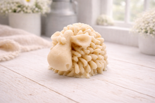 Load image into Gallery viewer, A highly detailed handmade vegan soap sculpted in the shape of a fluffy sheep with thick, textured wool and a smooth face, displayed on a light wooden surface in a farmhouse-style setting.
