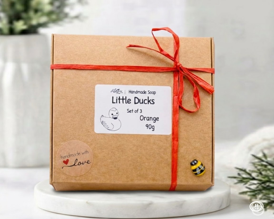 Gift box with 'Little Ducks' label and red ribbon on a wooden surface.
