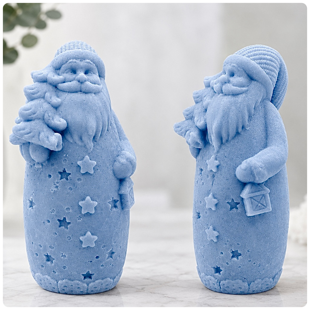 Two pastel blue Santa Claus soaps featuring knitted hats, detailed beards, Christmas tree decorations and star patterns, showcasing two different angles in a minimalist festive setting.